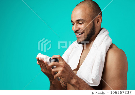 Happy african american man with towel holding shaving foam Happy african american man with towel holding shaving foam 106367837