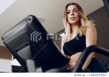 Fit curvy young blonde woman training in a cardio zone in a gym Fit curvy young blonde woman training in a cardio zone in a gym 106367850