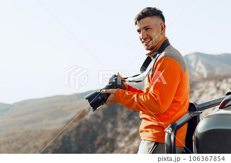 Young man traveler taking photos of mountains with professional camera 106367854