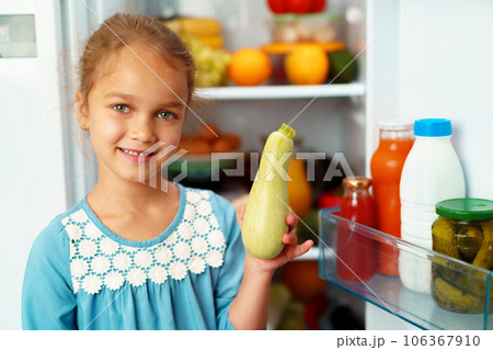 Little girl standing in front of a fridge and choosing food Little girl standing in front of a fridge and choosing food 106367910