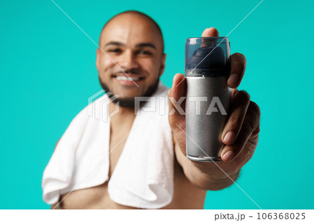 Happy african american man with towel holding shaving foam 106368025