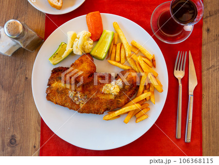 Portion of fried fish fillet with potato and vegetables 106368115