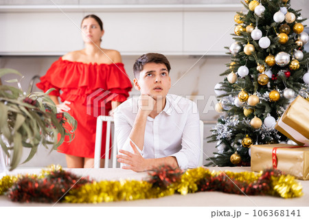 Furious young European man and woman in red dress yelling at each other during preparations for New Year in cuisine Furious young European man and woman in red dress yelling at each other during preparations for New Year in cuisine 106368141