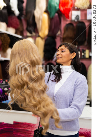 Woman choosing natural wig at specialty boutique Woman choosing natural wig at specialty boutique 106368273