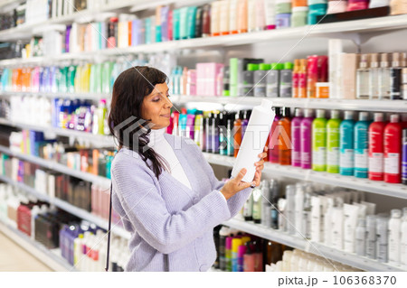Latin american woman looking for haircare products at cosmetics shop 106368370