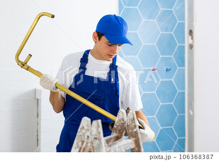 Professional plumber assembles and installs a new shower in bathroom Professional plumber assembles and installs a new shower in bathroom 106368387