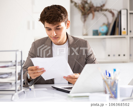 Male bookkeeper doing paperwork in workplace in office - checks accounting documents 106368502