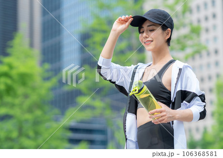 都会でジョギングの途中で休憩して水を飲む若い女性 106368581
