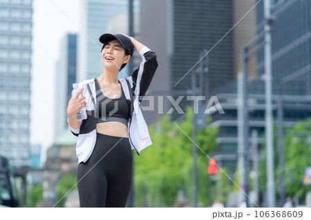 都会でジョギングの途中で休憩して水を飲む若い女性 106368609