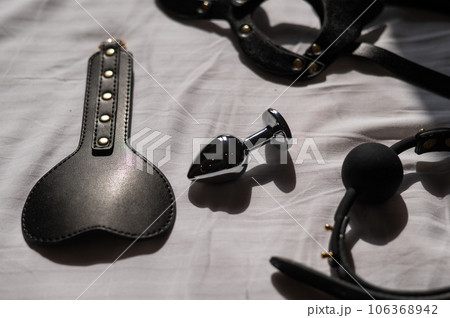 Black leather bdsm set on white sheet. Black leather bdsm set on white sheet. 106368942