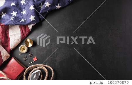 Happy Columbus Day concept. Vintage American flag, compass, paper boat, rope on dark stone background.  Flat lay, top view with copy space. 106370879