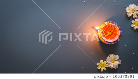 Happy Diwali - Clay Diya lamps lit during Diwali, Hindu festival of lights celebration. Colorful traditional oil lamp diya on blue background 106370891