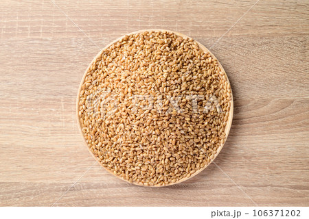 Whole wheat grain on plate with wooden background, Food ingredients, Table top view 106371202