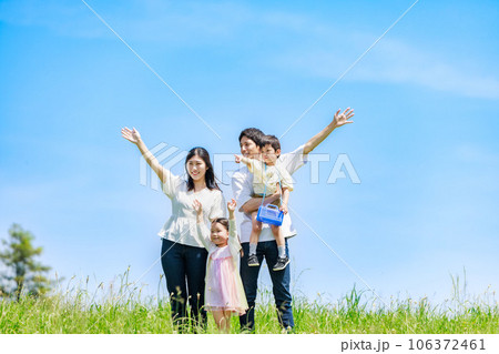 青空の草原を散歩する家族 106372461