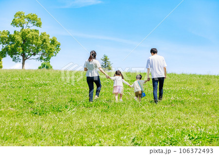青空の草原を散歩する家族 106372493
