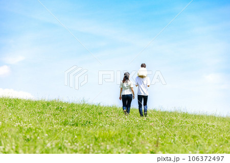青空の草原を散歩する家族 106372497