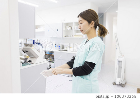 歯科治療イメージ　治療の準備で手袋をする歯科衛生士 106373258