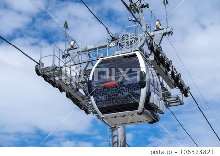 Close-up of a cable car cabin against the sky. Cable car trip to viewpoints in the mountains. During the trip by cable car Tourists enjoy beautiful views and experience exciting. Close-up of a cable car cabin against the sky. Cable car trip to viewpoints in the mountains. During the trip by cable car Tourists enjoy beautiful views and experience exciting. 106373821