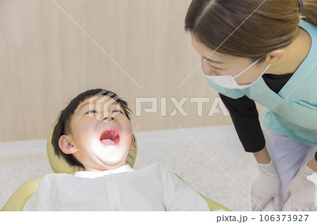 歯医者で口を開けた子供に話しかける歯科衛生士　歯科検診　治療 106373927