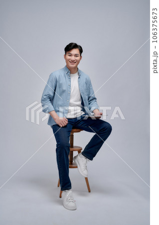 Image of young Asian man sitting on chair Image of young Asian man sitting on chair 106375673