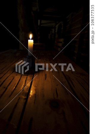 a candle in a dark room is on the table, lack of electricity, saving light, no gas and heat 106377535
