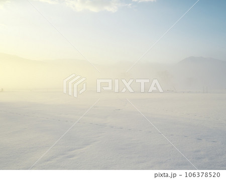 朝霧立ち込める千曲川の雪原から山なみを臨む 106378520
