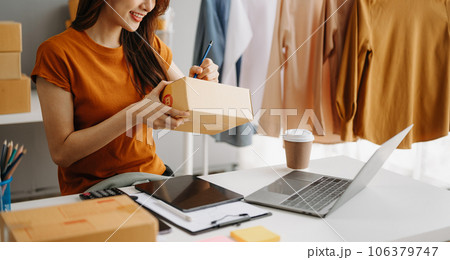 Young woman holding a smartphone, tablet showing payment success and credit card with yellow parcel box as online shopping concept in home office Young woman holding a smartphone, tablet showing payment success and credit card with yellow parcel box as online shopping concept in home office 106379747