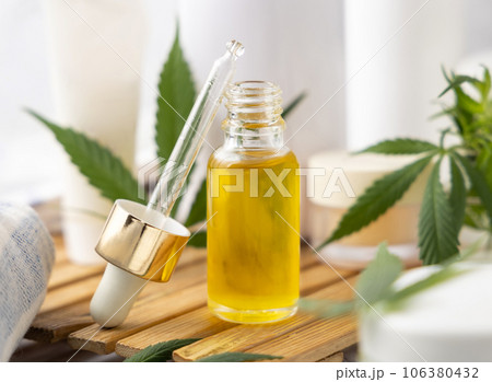 Dropper bottle with CBD oil near green cannabis leaves near bottles and towel close up Dropper bottle with CBD oil near green cannabis leaves near bottles and towel close up 106380432