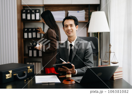 Asian lawyer man working with a laptop and tablet in a law office. Legal and legal service concept. Looking at camera in modern office. Asian lawyer man working with a laptop and tablet in a law office. Legal and legal service concept. Looking at camera in modern office. 106381082