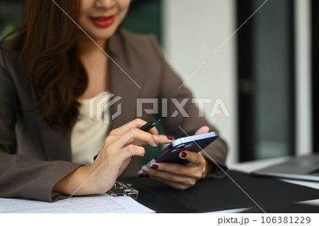Cropped shot of woman holding smartphone using mobile app, checking social media, texting message Cropped shot of woman holding smartphone using mobile app, checking social media, texting message 106381229