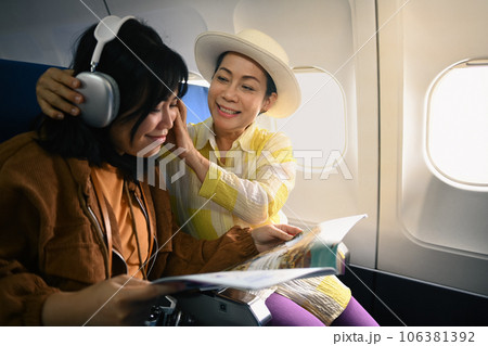 Positive senior woman and daughter listening to music during fly in airplane. Holidays and transportation concept 106381392