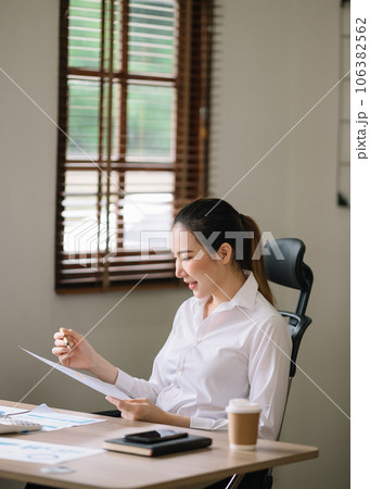 Confident business expert attractive smiling young woman typing laptop ang holding digital tablet  on desk in office.. 106382562