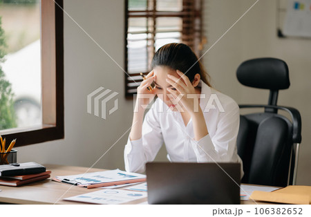 Asian business woman is stressed, bored, and overthinking from working on a tablet at the office... Asian business woman is stressed, bored, and overthinking from working on a tablet at the office... 106382652