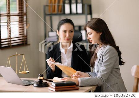udge gavel with scales of justice, Business and lawyer or counselor consulting and discussing contract papers with laptop and tablet at law firm in office... 106382720