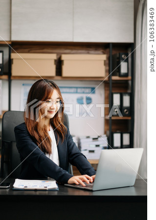 Confident Asian woman with a smile standing holding notepad and tablet at the modern office. 106383469
