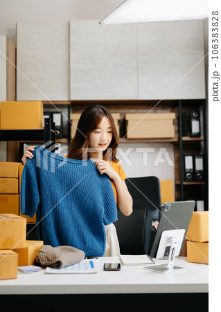 Fashion blogger concept, Young Asian women selling clothes on video streaming.Startup small business SME, using smartphone or tablet taking receive and checking. Fashion blogger concept, Young Asian women selling clothes on video streaming.Startup small business SME, using smartphone or tablet taking receive and checking. 106383828