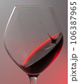 A falling drop of red wine in a glass, close-up. 106387965