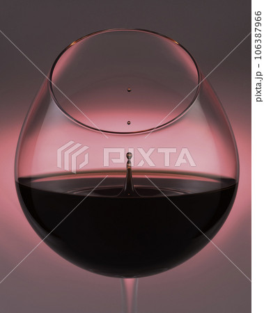 A falling drop of red wine in a glass, close-up. 106387966