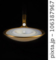 A drop of milk falls into a golden spoon. Black background, macro 106387967