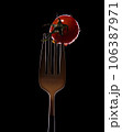Fork with small tomatoes on a black background 106387971