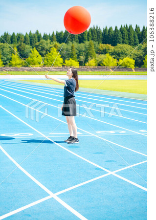 大きい赤い風船を持ちながら真夏の外ではしゃいでいる女性 大きい赤い風船を持ちながら真夏の外ではしゃいでいる女性 106388216