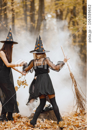 Three girls witches in forest on Halloween. Girls wearing black dresses and cone hats. Witches dance to make a magic potion. Three girls witches in forest on Halloween. Girls wearing black dresses and cone hats. Witches dance to make a magic potion. 106389662