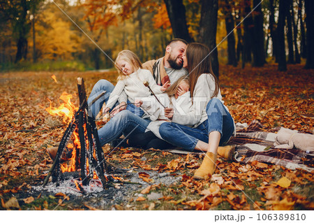 Family in a autumn park. Woman in a red sweater. Cute childrens with parents sitting near fireplace 106389810