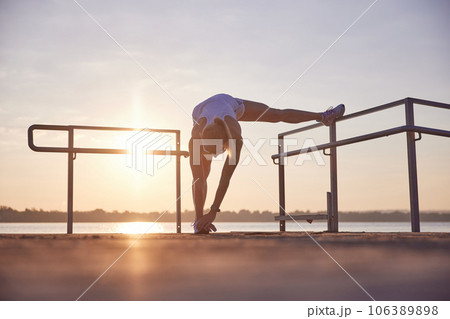 Young woman doing warming-up near seaside. Morning fitness exercise on beach, near the ocean on sunrise. Side legs stretching. Young woman doing warming-up near seaside. Morning fitness exercise on beach, near the ocean on sunrise. Side legs stretching. 106389898