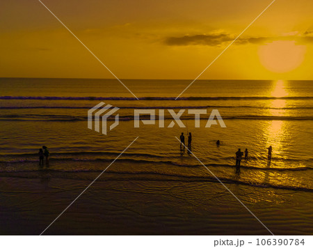 The twilight atmosphere at Legian Beach, Bali. Silhouettes of people enjoying the sunset while playing on the beach. The twilight atmosphere at Legian Beach, Bali. Silhouettes of people enjoying the sunset while playing on the beach. 106390784