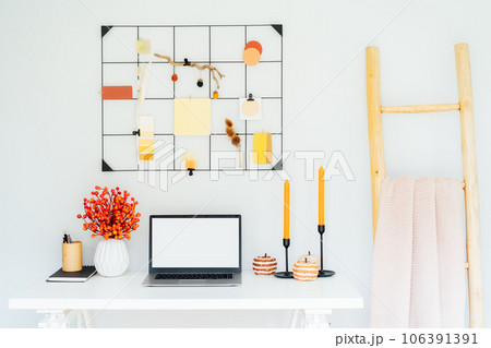 Home office desk with open laptop mockup, grid mood board with fall colors palette and seasonal decor like candles, flowers, pumpkins, plaid. Autumn inspiration and cozy mood. Hygge home fall decor 106391391