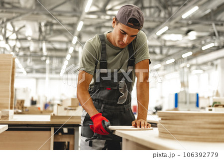 Young carpenter making wood furniture while working in joinery 106392779