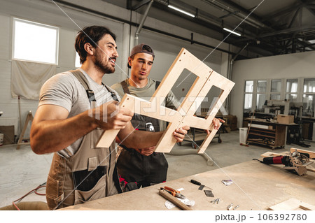 Two young men carpenters making furniture in warehouse of wood factory Two young men carpenters making furniture in warehouse of wood factory 106392780