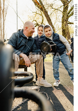 Father with his two sons on an outdoor sports ground in the park Father with his two sons on an outdoor sports ground in the park 106392816