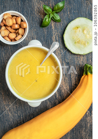 Zucchini vegetarian soup in a white plate and zucchin on a wooden background, top view Zucchini vegetarian soup in a white plate and zucchin on a wooden background, top view 106392865